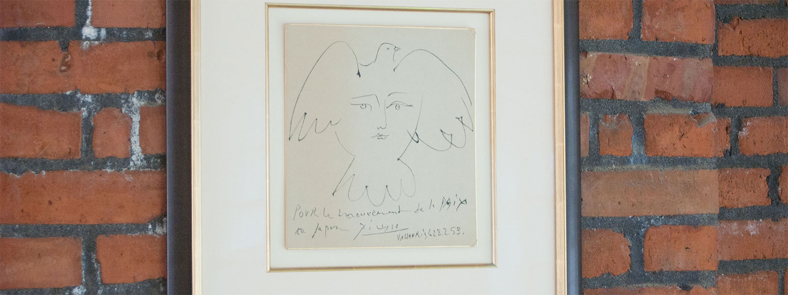 "La Visage de la Paix," by Pablo Picasso, framed art work on brick wall in UW Tacoma Library