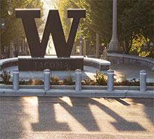 Steel W on UW Tacoma campus backlit by sun, with dramatic shadow in foreground.